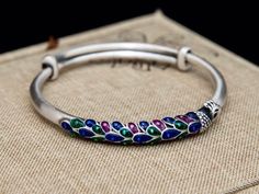 "Beautiful Enamel Peacock bangle bracelet for the upcoming season , made with 999 fine silver and multi colors of enamel , unique and stylish . Width: 3/10 \" ( 6mm ) Diameter: 60mm Adjustable Weight : 31 grams ♥️ For other fine silver bracelets , click here : https://www.etsy.com/shop/tibicollection?section_id=24787065 Return to my shop's home page, click here : https://www.etsy.com/shop/tibicollection" Peacock Design Bracelets For Festivals And Gifts, Peacock Design Bangle Bracelet Gift, Silver Bangle Bracelets Unique, Silver Anklets Designs, Solid Silver Bracelets, Peacock Jewelry, Neck Pieces Jewelry, Anklet Designs, Silver Bracelets For Women