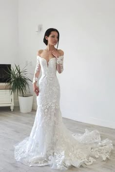 a woman in a white wedding dress posing for the camera with her hands on her hips