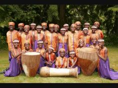 a group of african women in orange and purple outfits posing for a photo with drums