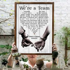 a woman holding up a framed poster with the words we're a team