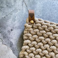 a close up of a woven bag with a wooden button on the end and rope around it