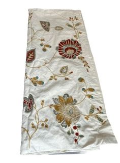 a white table runner with flowers and leaves on it