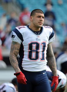 a football player standing on the field with his hands in his pockets and wearing red gloves