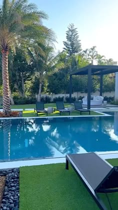 an empty swimming pool with lounge chairs and palm trees in the backgrouds