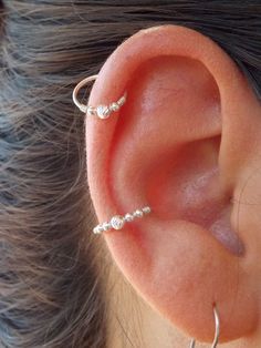 an ear with two small silver beads on it's side and one smaller white bead