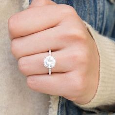 a woman's hand wearing a ring with a diamond in the middle and a white background