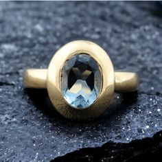 a gold ring with an aqua blue topazte stone in the center on a rock