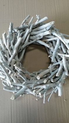 a wreath made out of driftwood sitting on top of a cardboard box with white paint