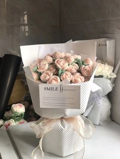 a bouquet of pink roses sitting on top of a white box next to other flowers