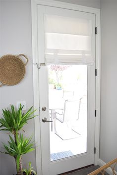 a white door with blinds on it and a potted plant next to the door