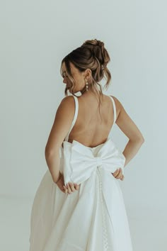 a woman in a white dress with a big bow on her back