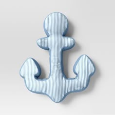 a blue and white striped pillow with an anchor on the front, sitting against a gray background