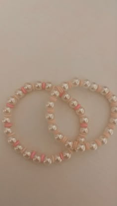 two bracelets with pink and white beads are on the table next to each other