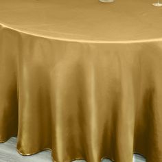 a table with a gold cloth on it and two wine glasses sitting on the table