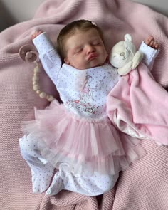 a baby is sleeping on a pink blanket with a teddy bear in it's arms