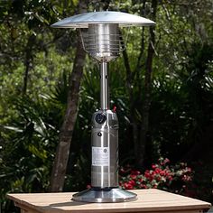 a patio heater sitting on top of a wooden table in front of some trees