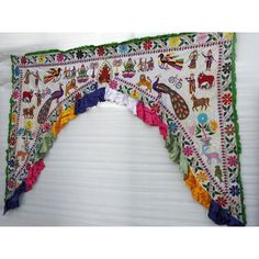 an embroidered curtain with animals and other things on it's side, hanging from the ceiling