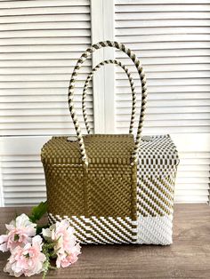 two woven bags sitting next to each other on a wooden table with flowers in the foreground