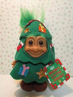 a trolly doll with green hair holding a christmas tree ornament in it's hand