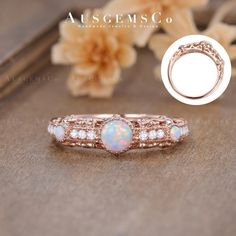 an opal and diamond ring is shown on a table with flowers in the background