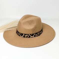 Taupe flat brim hat with a leopard print hat bad around the crown. This hat is pictured on a white background with ivory pompous grass laying partially on the brim. Beige Flat Brim Hat For Fall, Fall Beige Flat Brim Hat, Winter Vacation Hat With Short Brim, Winter Vacation Fedora With Short Brim, Beige Fedora Hat For Fall, Curved Brim Fedora For Beach In Fall, Curved Brim Fedora For Beach And Fall, Flat Brim Felt Hat For Vacation, Adjustable Wide Brim Boater Hat For Fall