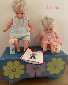 two dolls sitting on top of a blue table