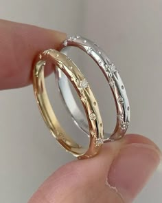 two gold wedding bands with diamonds on each one hand, in front of a white background