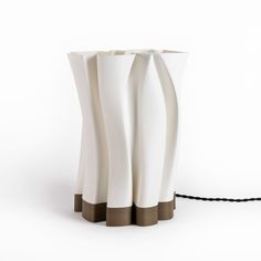 a white vase with three brown stripes on the bottom and one black cord attached to it