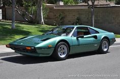 a green sports car parked on the side of the road in front of a house