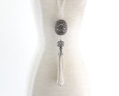 "A beautiful oxidized Turkish Sterling Silver Tassel is paired with a large oval Balinese Sterling Silver bead and wire wrapped together onto a long sterling silver chain. This statement necklace is classic, elegant and fun. Can easily be dressed up or worn casually. The large oval Bali bead measures about 22mm by 26mm. The chain measures 32\" and the pendant and coordinating bead dangle about 4 3/4\" from that. No clasp necessary as the long chain fits right over your head. Sterling Silver is . Silver Bohemian Lariat Tassel Necklace, Handmade Silver Long Tassel Necklace, Elegant Silver Dangle Tassel Necklace, Elegant Handmade Silver Long Necklace, Elegant Oxidized Finish Dangle Necklaces, Elegant Oxidized Dangle Necklace, Silver Long Necklace With Tassels, Elegant Oxidized Oval Pendant Necklace, Sterling Silver Name Necklace