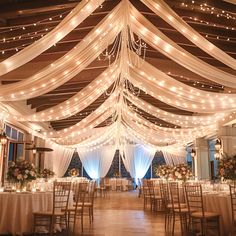 an indoor wedding venue with white draping and lights