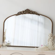 a mirror sitting on top of a white dresser next to a vase and candle holder