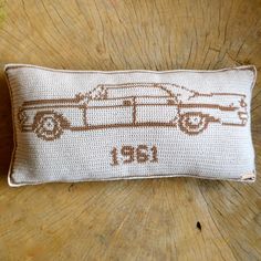 a pillow with a car on it sitting on top of a wooden table next to a piece of wood