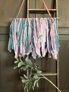 an old ladder is used as a wind chime with ribbons hanging from it's sides