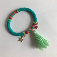 a bracelet with tassels and charms is shown on a white surface, it has a star charm in the middle