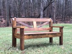 a wooden bench sitting on top of a lush green field next to a wooded area