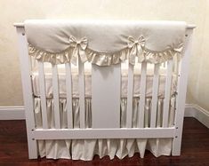 a white crib with ruffles and bows on the bedding is shown