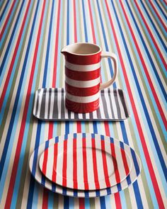 a striped table cloth with red, white and blue stripes on it has a coffee cup in the middle