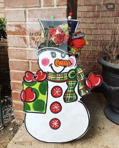 a snowman with a top hat and scarf standing in front of a brick wall