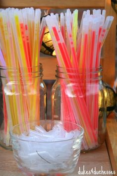 there are many different colored drinking straws in the glass cup on the table next to each other