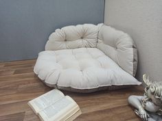 a white chair sitting on top of a hard wood floor next to an open book