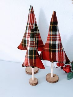 two red and black plaid christmas trees on wooden stands