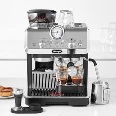 an espresso machine sitting on top of a counter next to some donuts