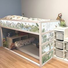 a child's bunk bed with an animal theme on the side and shelves below it