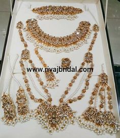 an elaborate necklace and earring set in white box with gold trimmings on it