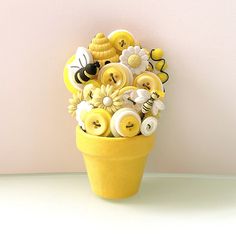 a yellow vase filled with buttons and flowers