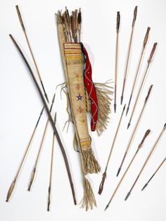 an assortment of arrows and sticks laid out on a white surface