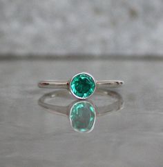 This Tiny Emerald Ring is the perfect addition to your jewelry collection. With its dainty design and simple mini silver band, it adds a touch of elegance to any outfit. Whether you wear it alone or stack it with other silver rings, this minimalist ring is sure to make a statement. The green stone adds a pop of color and brings a refreshing vibe to your look. Get ready to shine with this silver stackable ring! Material - 925 Sterling Silver Gemstone Name - CZ Stone Shape - Round Stone Size - 5 M Simple Tiny Stackable Round Rings, Simple Tiny Round Stackable Rings, Tiny Simple Round Stackable Rings, Dainty Bezel Set Midi Rings With Round Band, Silver Dainty May Birthstone Ring, Dainty Green Jewelry With Simple Design, Dainty Midi Rings With Bezel Setting, Simple Solitaire Midi Rings, Minimalist Adjustable Emerald Ring