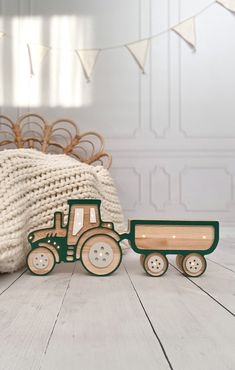 a wooden toy tractor and trailer sitting on a white wood floor next to a blanket