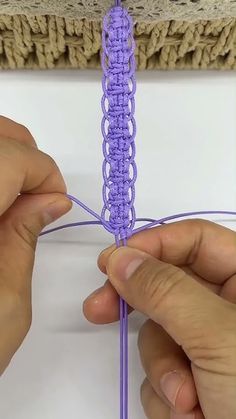 someone crocheting the end of a piece of purple yarn with their hands on it